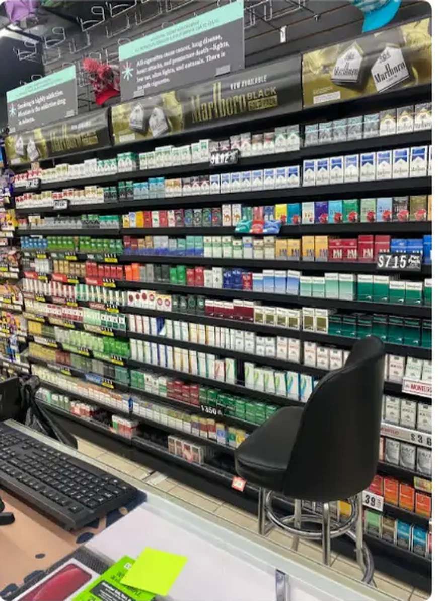Mega Tobacco Vape & Wireless full cigarette wall of tobacco packs behind the counter with the register station in view