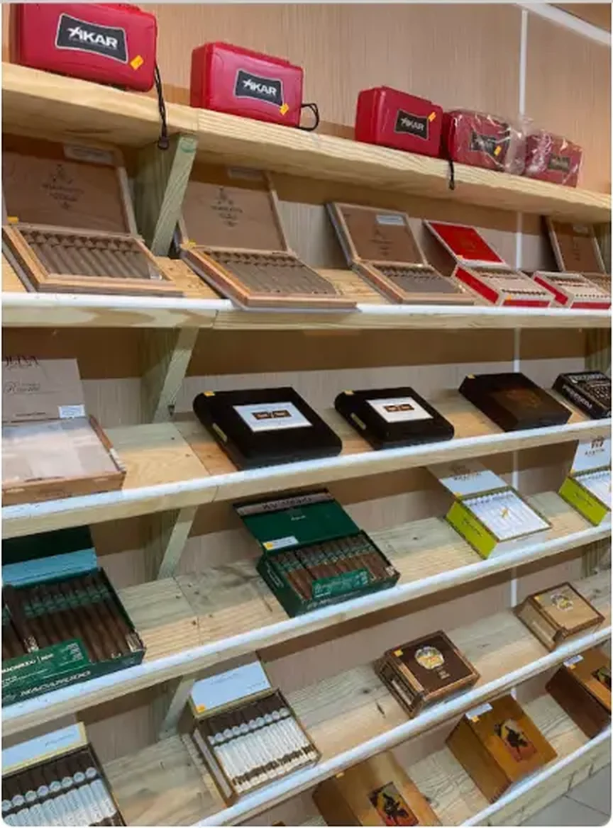Mega Tobacco Vape & Wireless angled view of cigar shelving with boxed cigars and red cigar cutter cases