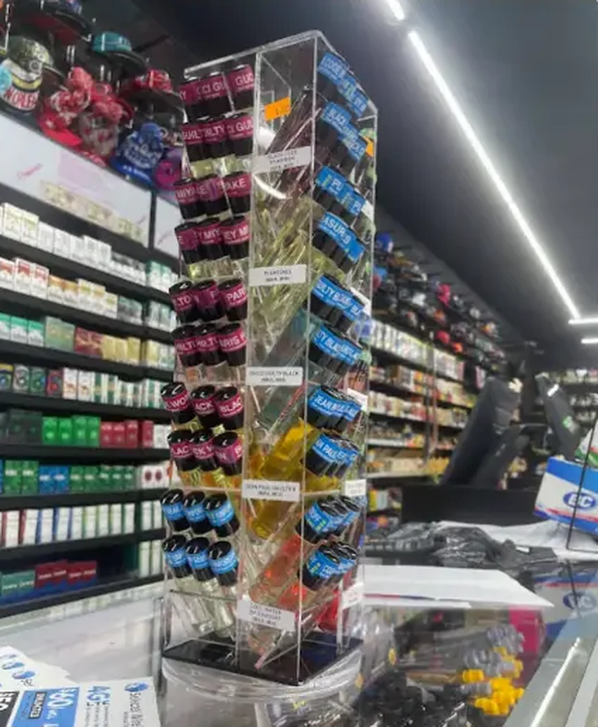 Mega Tobacco Vape & Wireless vape and e-liquid display tower on the counter with wall shelving behind it