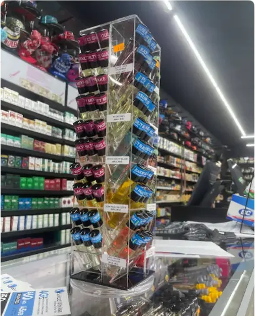 Mega Tobacco Vape & Wireless clear rotating tower of vape pods and e-liquid bottles beside the counter