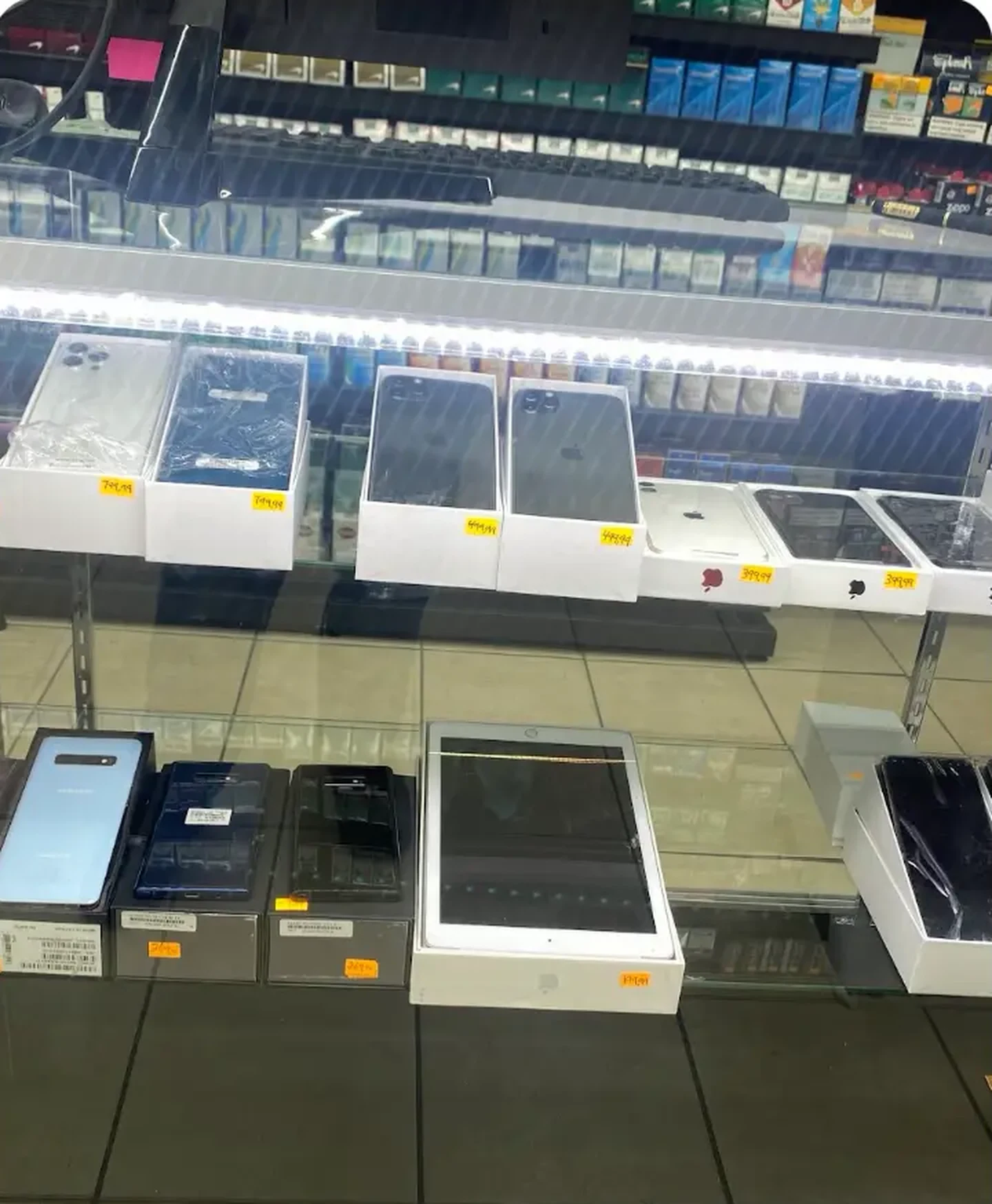 Mega Tobacco Vape & Wireless interior glass display case of boxed phones and tablets under lit shelving inside the Scotland Neck store