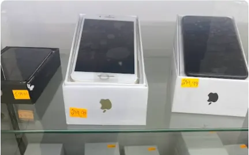 Boxed Apple phones sitting in the lit glass display case at Mega Tobacco Vape & Wireless