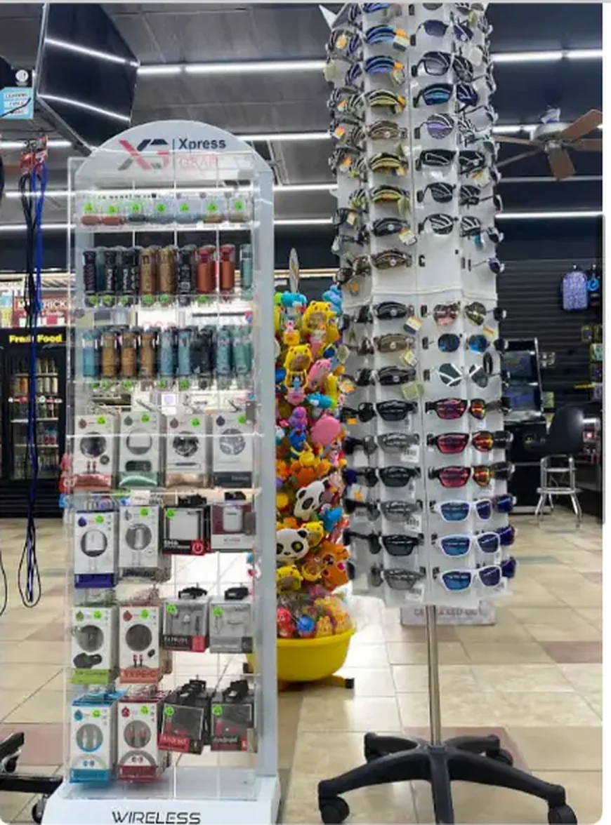 Mega Tobacco Vape & Wireless wireless accessory tower with earbuds, chargers and cables next to a sunglasses rack